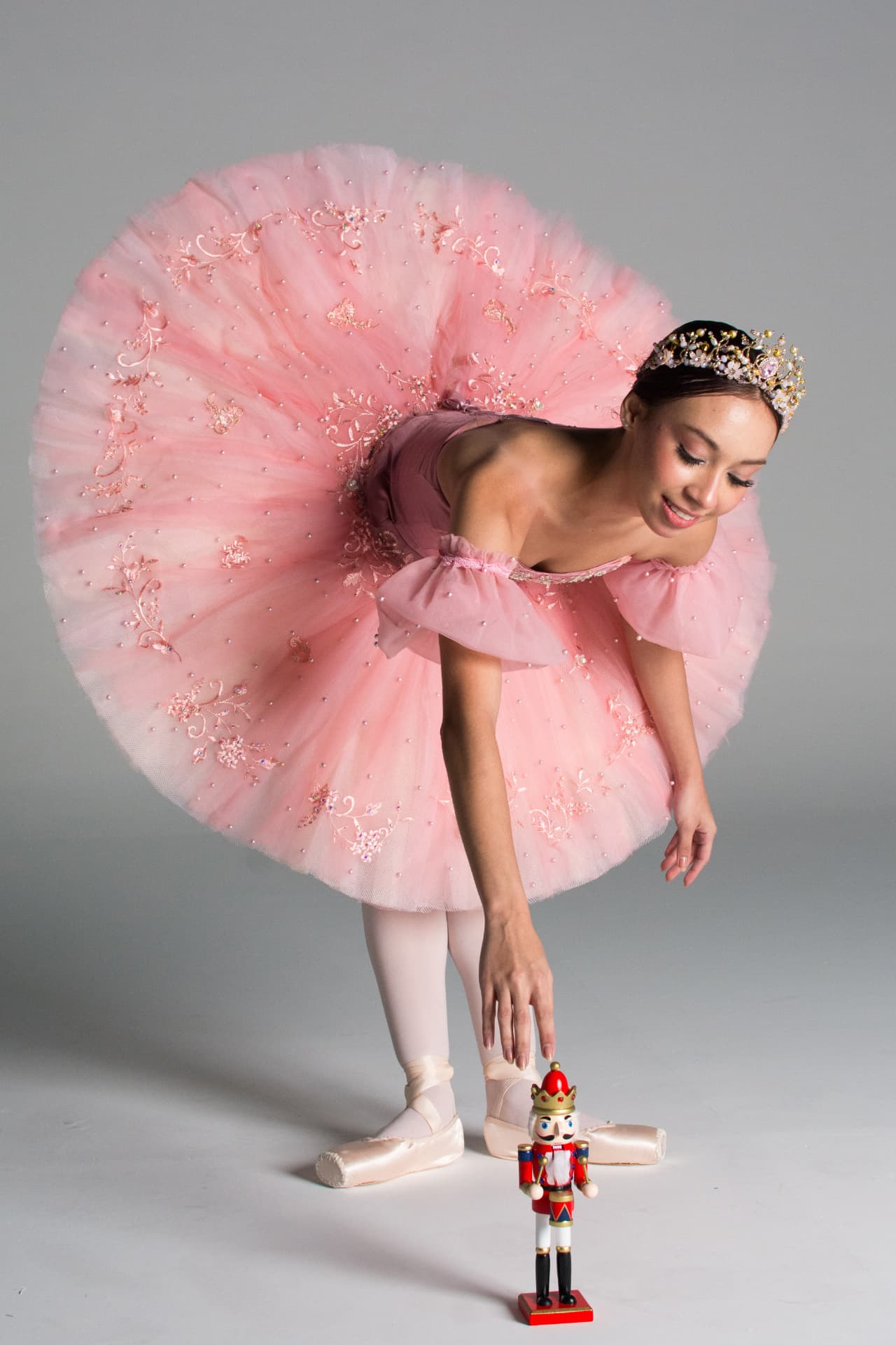 Bailarina em tutu rosa inclinada sobre o Quebra-Nozes